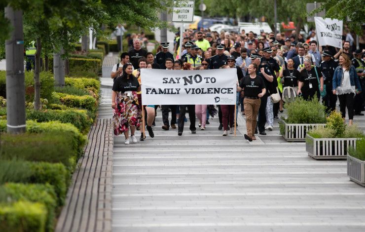 A crowd walks behind the Walk Against Family Violence banner