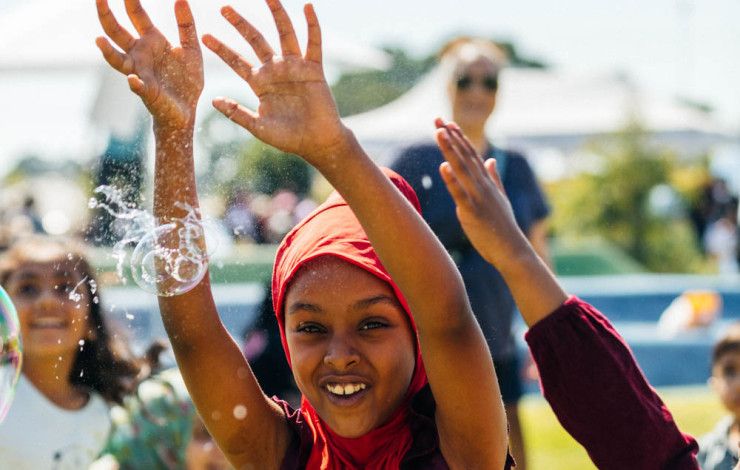 A smiling girl popping bubbles with her hands