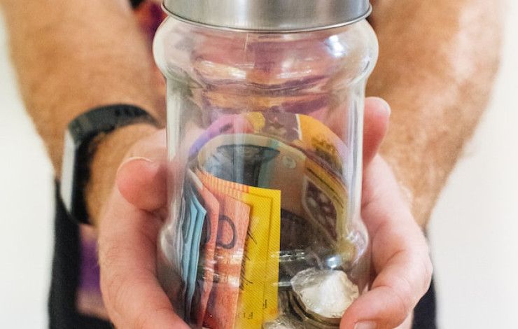 Man's hands holding glass jar full of money.