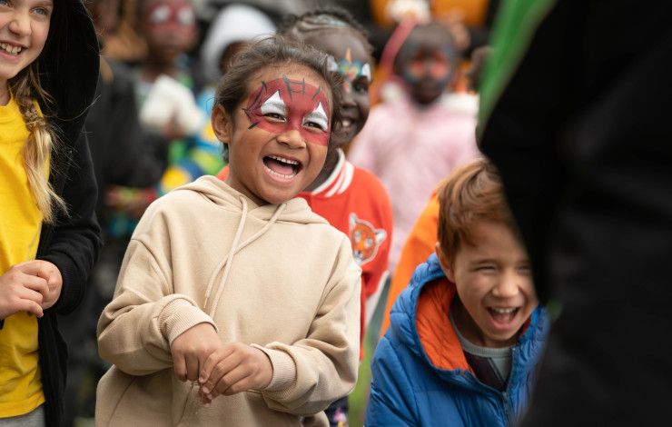 A laughing child with face painted like spiderman