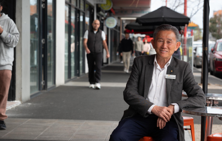 Councillor Richard Lim sitting on street furniture in Springvale