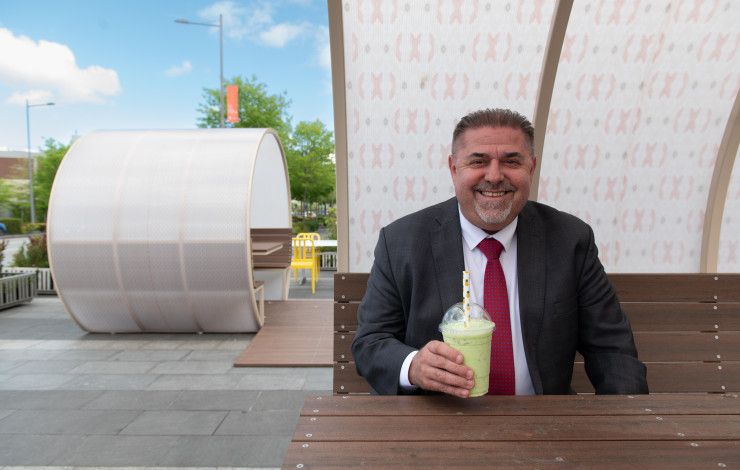 Councillor Jim Memeti enjoying a juice while sitting inside an outdoor dining pod