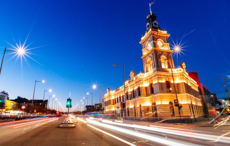 Heritage building with a clocktower lit up at dusk.