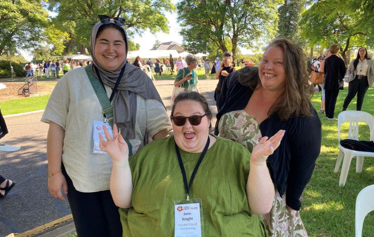 Three people smiling and waving at the camera.
