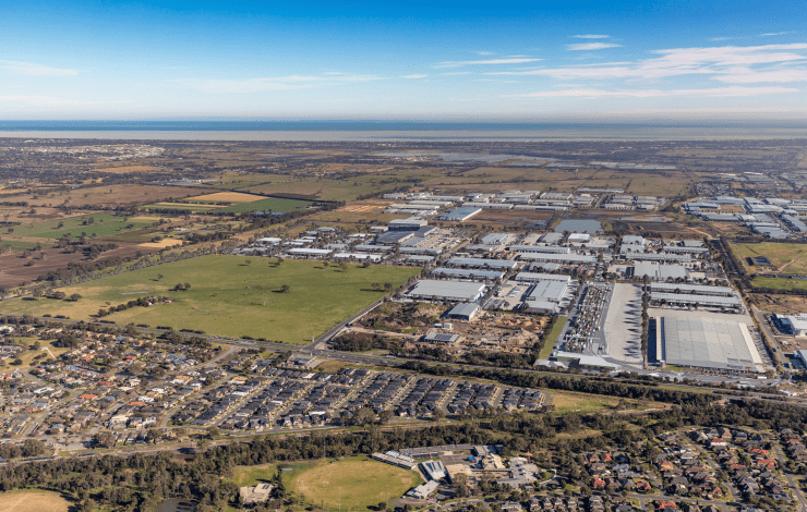 A view from above of a large suburb including housing, an industrial estate and open green paddocks