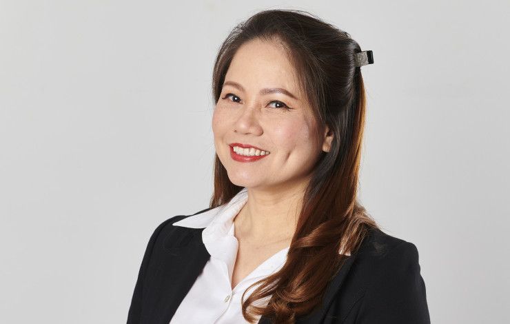 A woman dressed in a black suit and white shirt smiles at the camera.