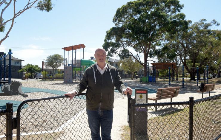 Man standing in an open gateway leading to a park