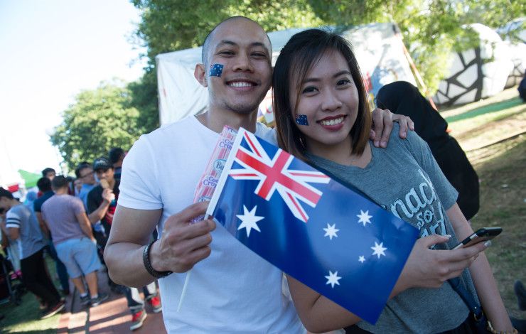 Two smiling people holding an Australian Flag