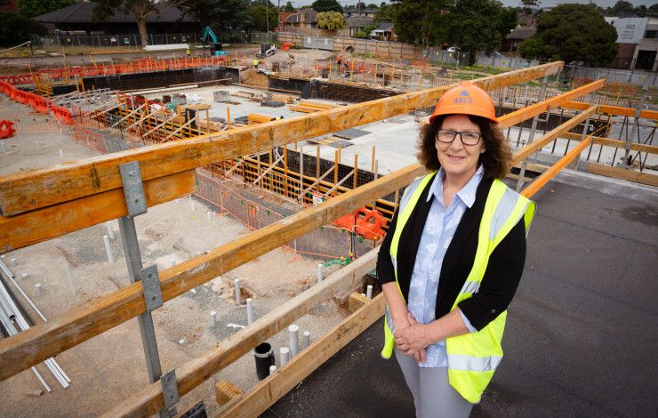 A woman dressed in a high vis vest and a hard hat stands on a platform overlooking a worksite
