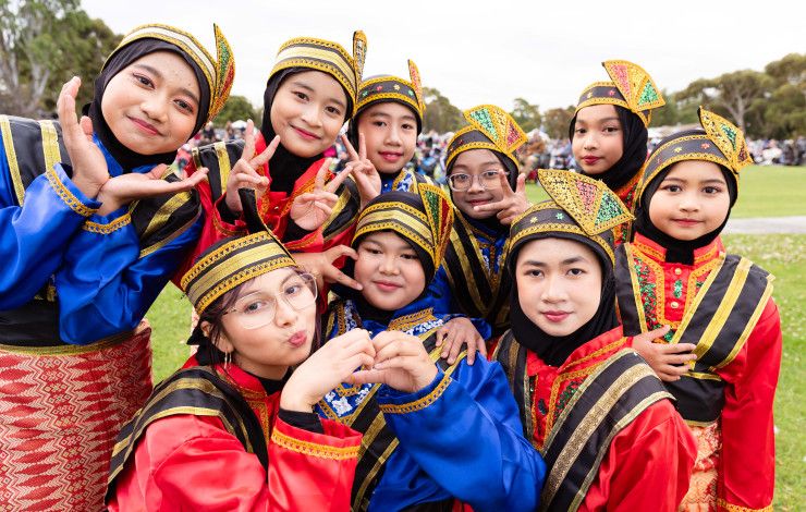 A group of smiling children wearing traditional Indonesian clothing