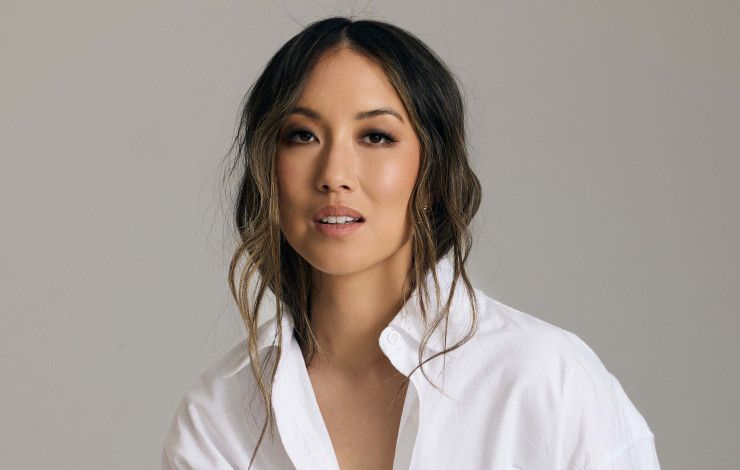 A smiling woman posing in a white shirt and black pants