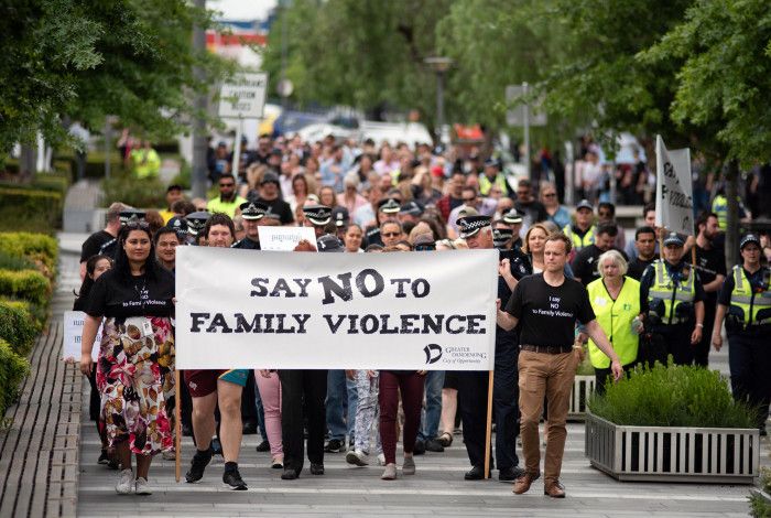 A large group marching with a sign saying 'We say no to family violence'