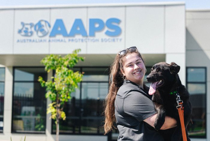 Happy woman hugging a dog in front of the AAPS building.