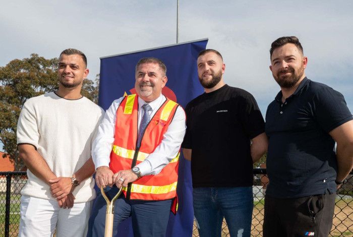 Four men standing together while one leans on a shovel.