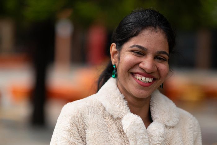 Young woman in a fluffy white coat smiling at the camera.