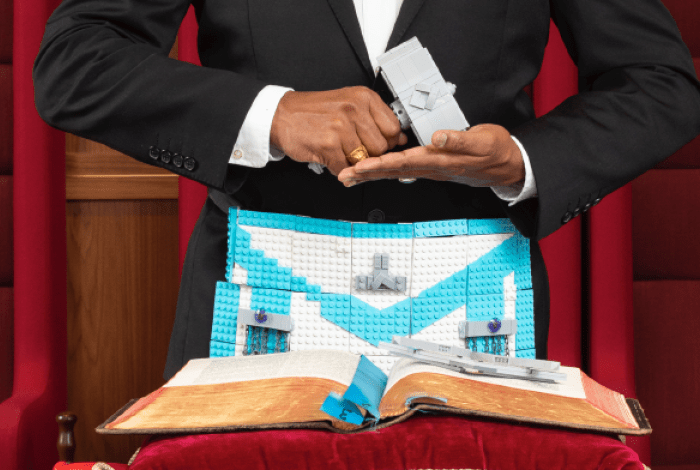 a person of colour holding a gavel made from LEGO