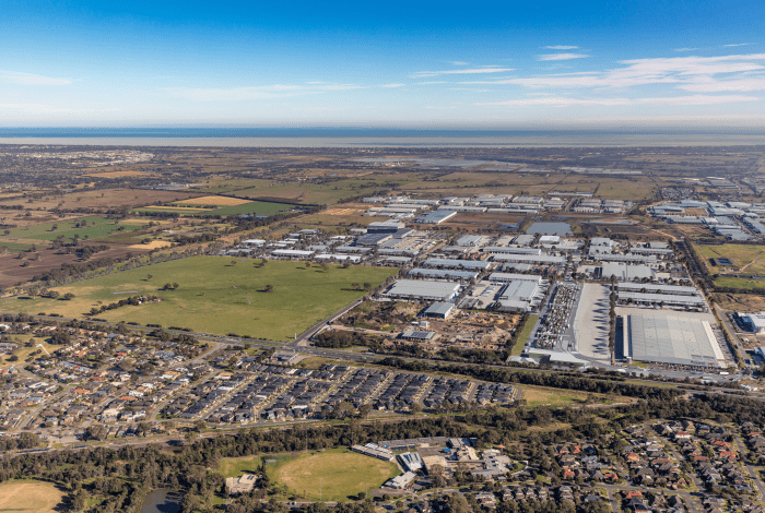A view from above of a large suburb including housing, an industrial estate and open green paddocks