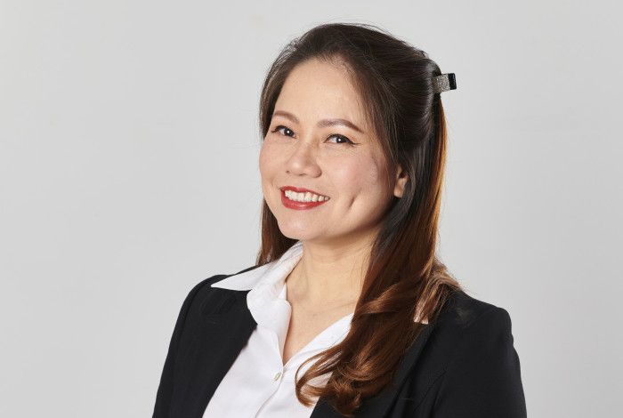 A woman dressed in a black suit and white shirt smiles at the camera.