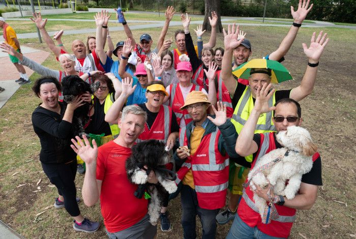 Group of Parkrun Volunteers smiling with their arms up