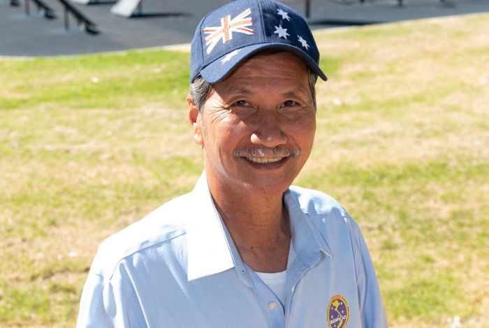 Smiling Vietnamese man wearing a hat featuring the Australian flag.