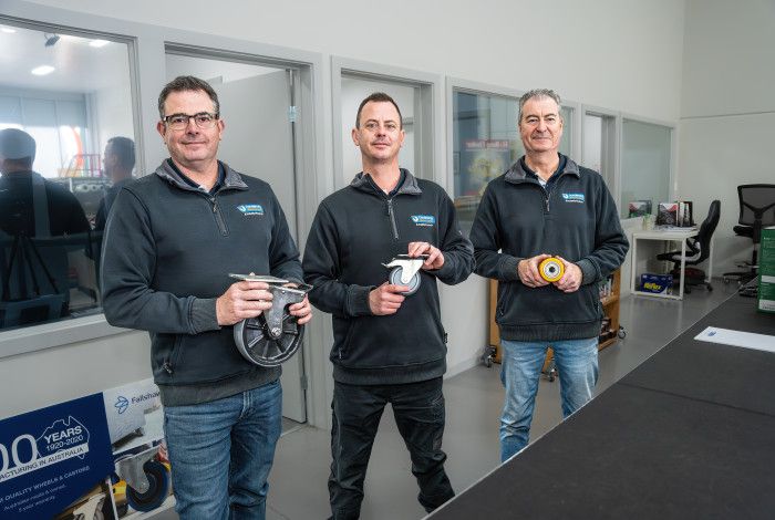Three people standing behind a counter in a shop.