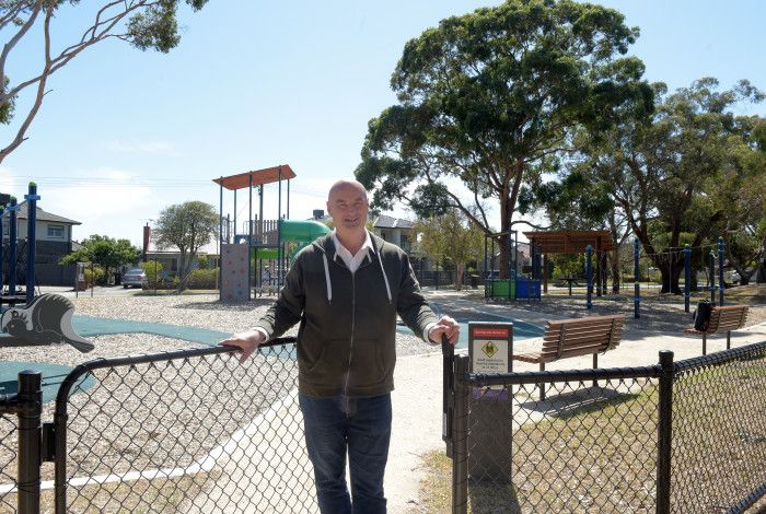 Man standing in an open gateway leading to a park