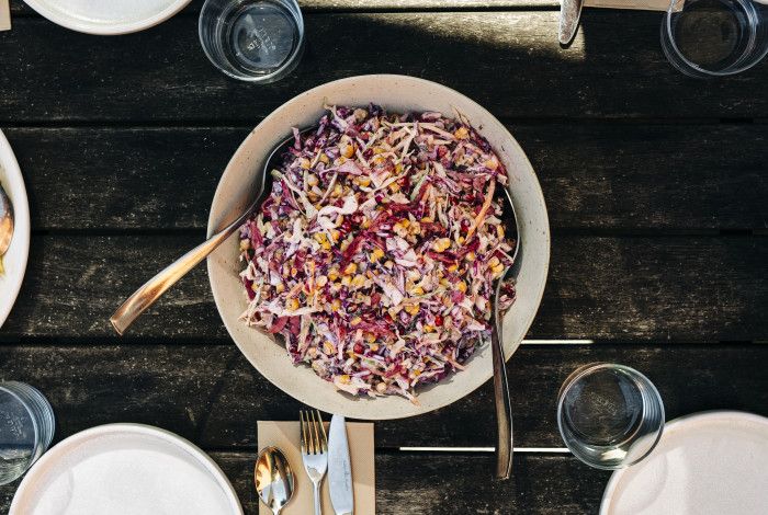 A bowl full of pomegranate salad on a dining table with cutlery.