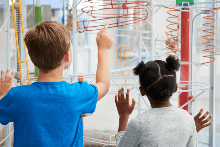 Two children looking at a ball obstical course. 