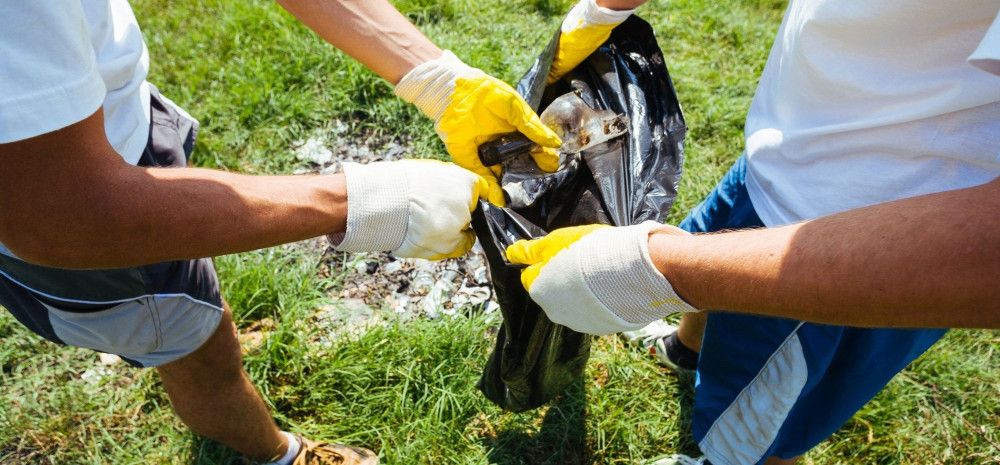 Two people putting litter into bag