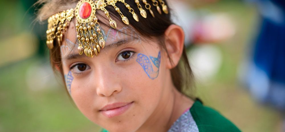 Young girl with headdress and mermaid tail face paint