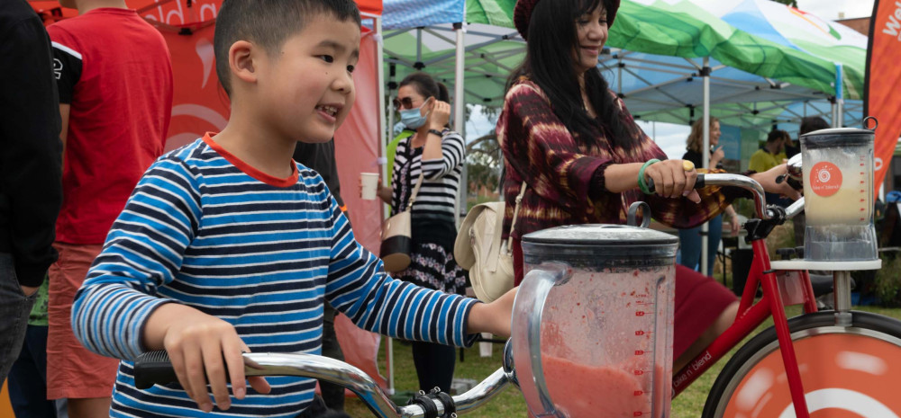 A child rides a bike to power a blender mixing a smoothie.