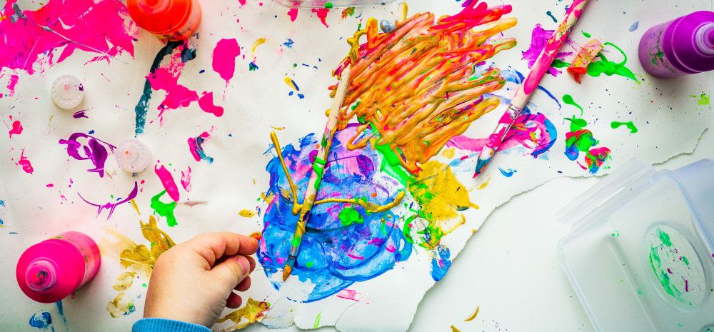 An overhead shor of a child's hand painting with bright colours