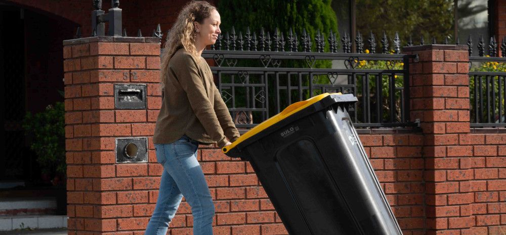 Resident pushing recycle bin out to the curb