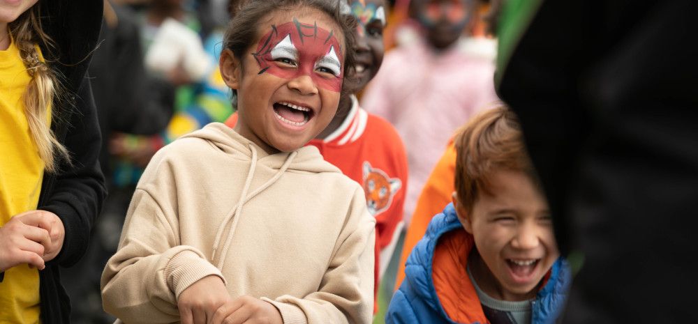 A laughing child with face painted like spiderman
