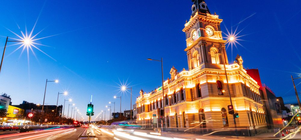 Heritage building with a clocktower lit up at dusk.