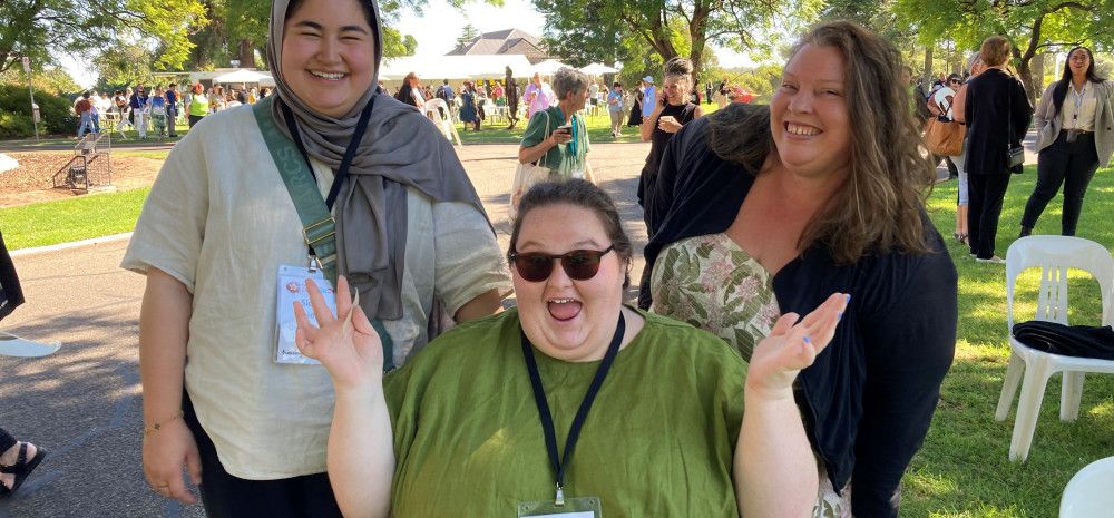 Three people smiling and waving at the camera.