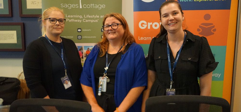 Three people standing in front of some banners.