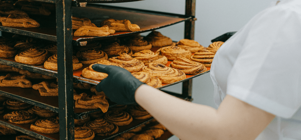 A baker loading pastries on to a rack.