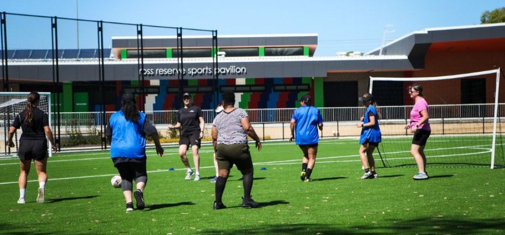 Women kicking a soccer ball on a soccer pitch