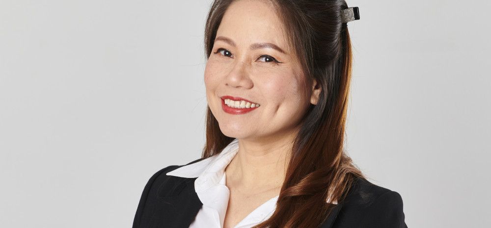 A woman dressed in a black suit and white shirt smiles at the camera.