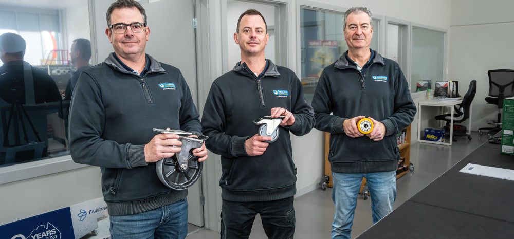 Three people standing behind a counter in a shop.