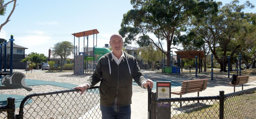 Man standing in an open gateway leading to a park