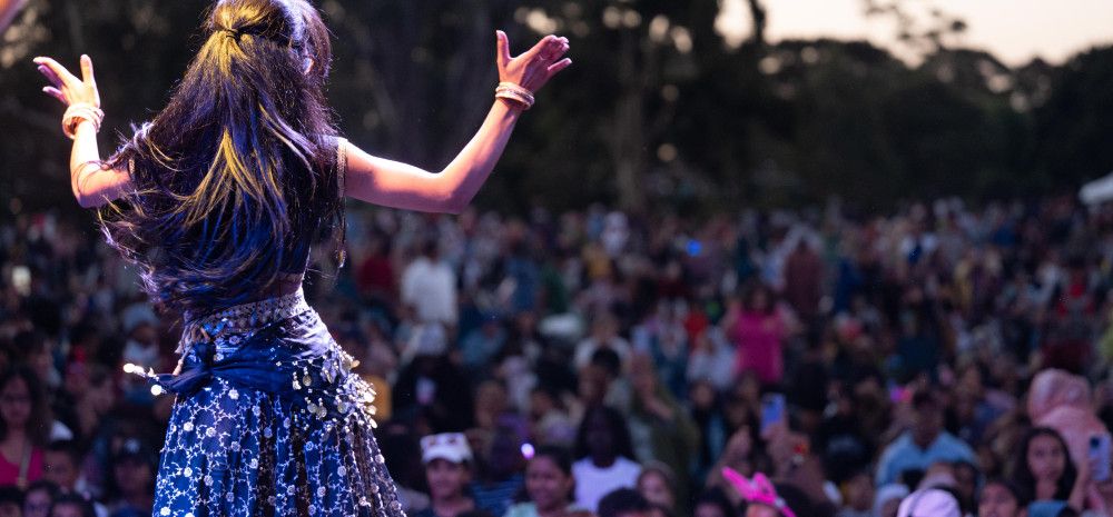 A woman dances on stage in front of a large crowd