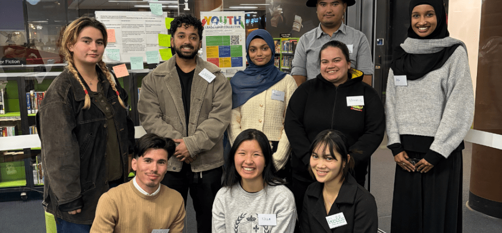 A group of smiling youth some in a line behind others kneeling on the ground.