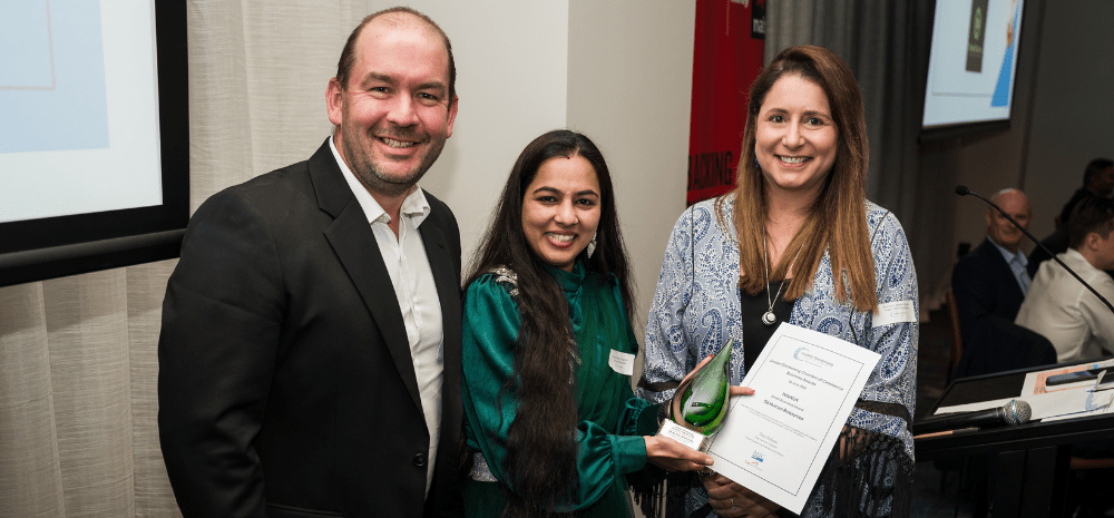Three people with one holding an award and certificate