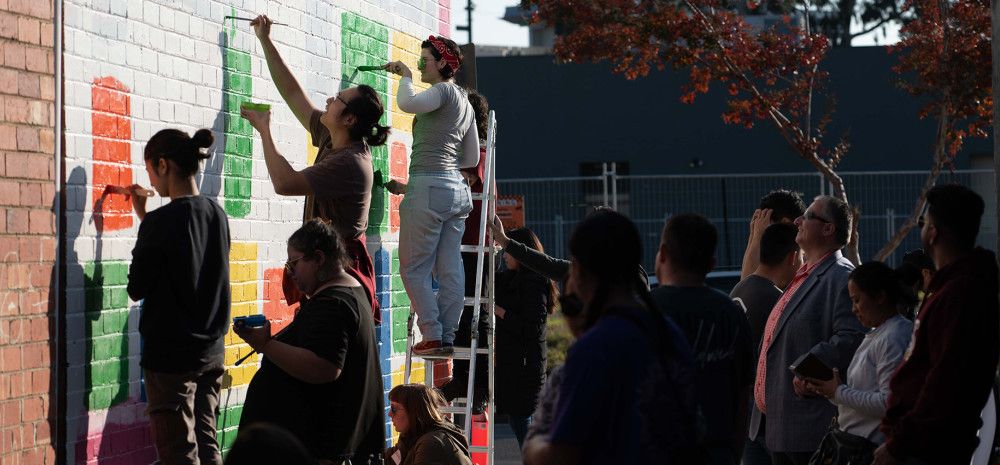 People watching people painting a mural