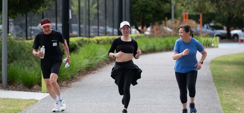 A man and two women are running in a track at Dandenong Park