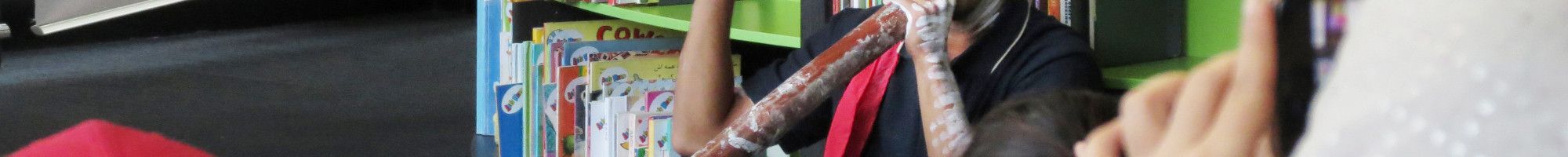 Photo of a man playing a didgeridoo in the library