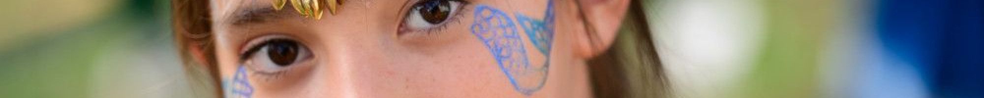 Young girl with headdress and mermaid tail face paint