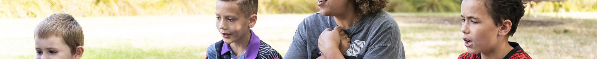 a group of people sitting on a rug outside